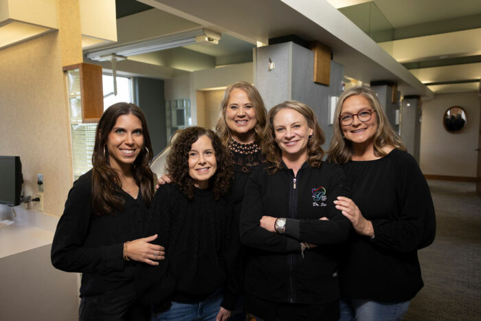 Dr. Gotwalt and her all-female dental team smiling together in their family dental office, showcasing a warm, welcoming environment.